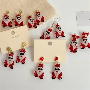 Detail of handmade beaded Santa Claus earrings with red bows and gold accents