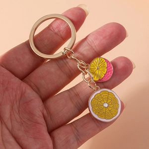 Detailed close-up of a golden keychain featuring realistic lemon and citrus fruit slices