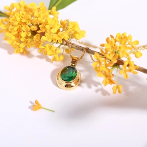 Close-up of gold 18k plated necklace with oval emerald gemstone and elegant floral accents