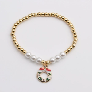 Détail du charm couronne de Noël sur un bracelet de perles dorées et perles blanches