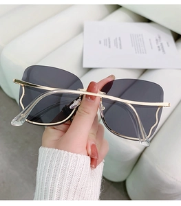 Detail of rimless gradient sunglasses featuring gold metal temples and wave patterns