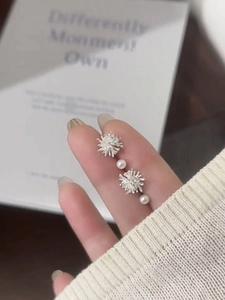 Close-up of sparkling star-shaped silver pearl earrings held in hand for a luxury look