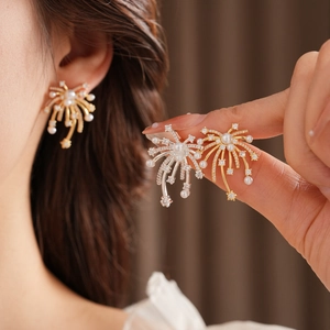 Detail of 18K gold plated fireworks earrings with pearls and crystals on a model