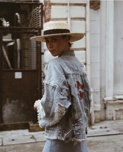 Close-up of a flat top straw boater hat with black ribbon and frayed denim jacket