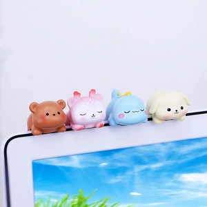 Close-up of cute animal figurines including bear and deer on a computer monitor edge