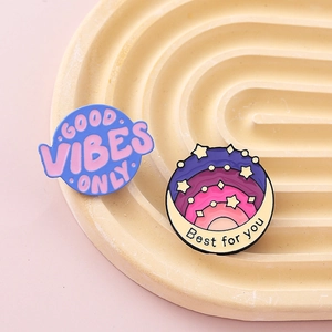 Detail of Good Vibes Only and Best For You colorful enamel pins on a textured tray