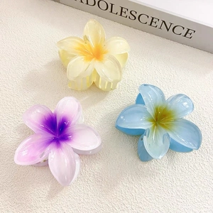 Close-up of three gradient resin plumeria hair claws in yellow, purple and blue