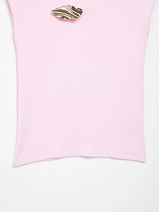 Detail of light pink knit top featuring a textured gold irregular leaf-shaped metal buckle