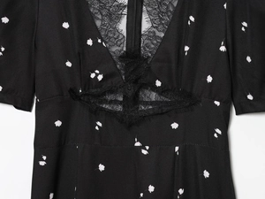 Detail des V-Ausschnitts mit schwarzem Blumenmuster und feiner Spitzenapplikation