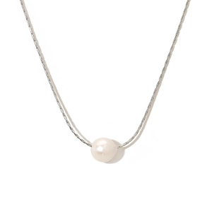 Vue macro détaillée d'une perle blanche lustrée sur un collier à chaîne fine en métal argenté