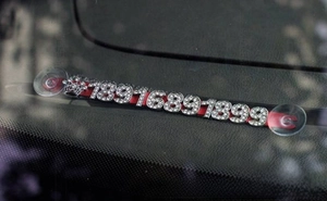 Detail of red car parking phone plate with sparkling rhinestone numbers and crown charm