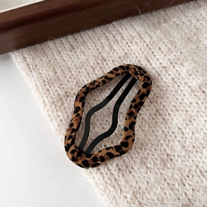 Close-up of leopard print fabric BB hair clip on soft knit background for women