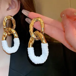 Boucles d'oreilles ovales torsadées dorées avec détails en similicuir blanc élégant