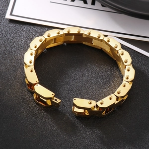 Detail eines goldenen Punk-Gliederarmbands mit Nietbolzen auf schwarzem Hintergrund