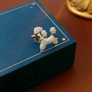 Detailed macro view of a silver poodle brooch with sparkling cubic zirconia on a gift box