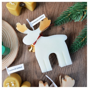 Macro view of handmade white elk candle with golden antlers and festive red ribbon