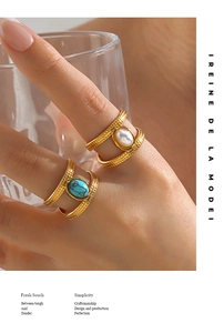 Detail of gold double-layer rings with turquoise and pearl on model holding a glass