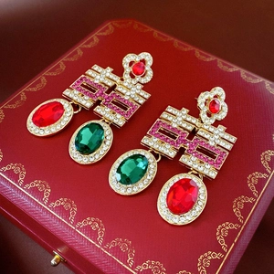 Gros plan de boucles d'oreilles chinoises Xi avec gemmes rouges et vertes en boîte