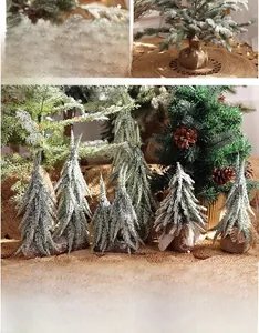Detail of mini snowy Christmas trees with pine cones and burlap base in warm lighting