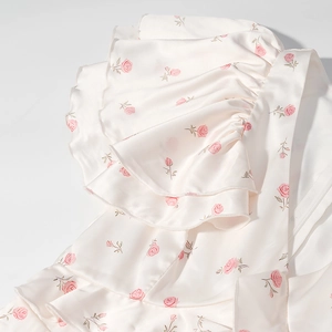 Détails de la robe en satin avec bords à volants et motifs délicats de roses roses