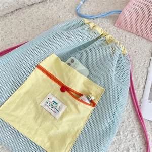 Detailed shot of mesh backpack with contrast front pocket, zipper, and brand logo patch