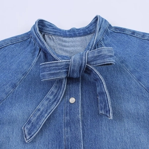Detail der Jeanshemd-Halslinie mit Schleife und poliertem, weißem Knopf-Design
