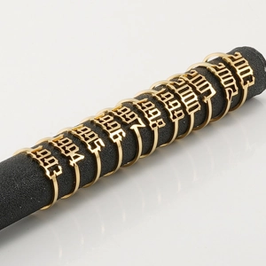 Gold stainless steel 18K lucky year rings from 1993 to 2003 displayed on black bar