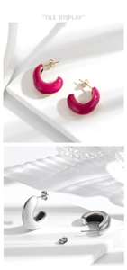 Detail of C-shaped enamel earrings in magenta and white with gold and silver finish