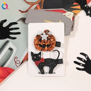 Detail of Halloween hair clips with glittery pumpkin and black cat designs on card