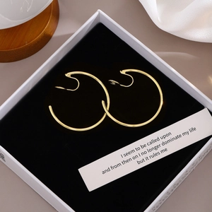 Detail of elegant gold hoop clip-on earrings inside a premium white jewelry gift box