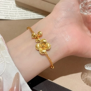 Detail of 24K gold plated flower bracelet with matte texture beads on a female wrist