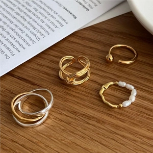 Detail of minimalist S925 silver knot rings and pearl bands on a wooden background