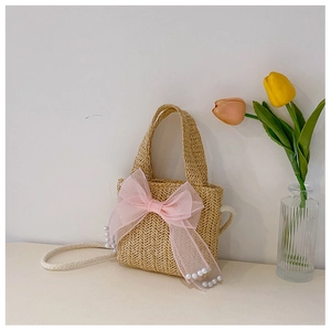 Detail of straw bag with pink gauze bow and pearl beads featuring woven handle and strap