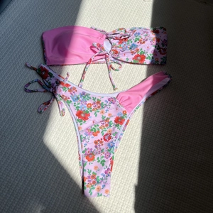 Détail à plat d'un bikini bandeau à fleurs avec culotte rose nouée sur les côtés