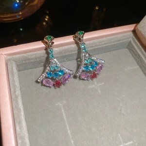 Detail of fan-shaped silver earrings with colorful gemstones in a luxury jewelry box
