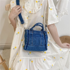 Detail view of the washed blue denim fabric and adjustable shoulder strap of the casual bag