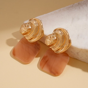 Macro detail of amber resin square pendant with textured gold irregular metal stud earring