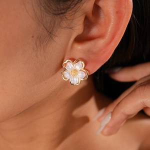 Close-up of elegant flower stud earring with gold borders and resin petals worn by a model