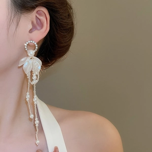 Detail of floral tassel earrings with white petals and dangling pearls on model