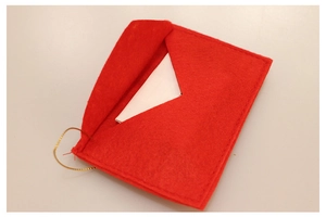 Close-up of red felt Christmas envelope ornament with golden string and a white card