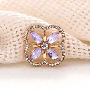 Macro shot of gold-plated clover brooch with purple crystal and clear rhinestones