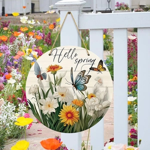 Round wooden Hello Spring welcome sign with butterfly and flower patterns on a fence