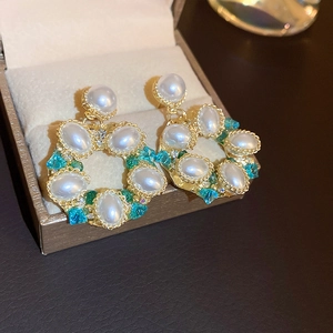 Vintage gold hollow flower earrings with faux pearls and blue crystals in a jewelry box