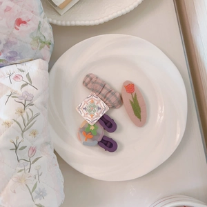 Detailed close-up of floral embroidery hair clips and pastel hair accessories on ceramic plate