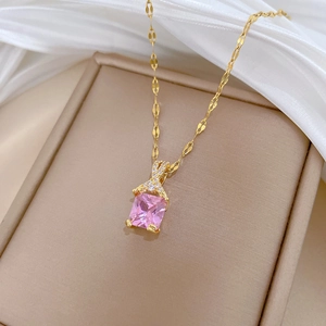 Close-up of gold necklace with pink square gemstone and sparkling crystal cross detail