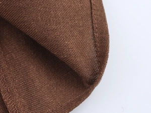 Detailed close-up of dark brown linen-textured fabric with neat stitching on the edge