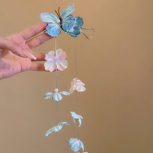 Detail of fabric butterfly hair clip with pearl accents and long floral fringe tassels