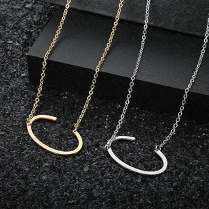 Macro view of minimalist gold and silver letter pendants on matte black background
