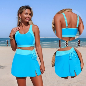 Two-piece bright blue split swimsuit with tank top and side-tie skirt on beach background