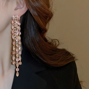 Close-up of long pink tassel earrings with rose gold plating and sparkling crystals